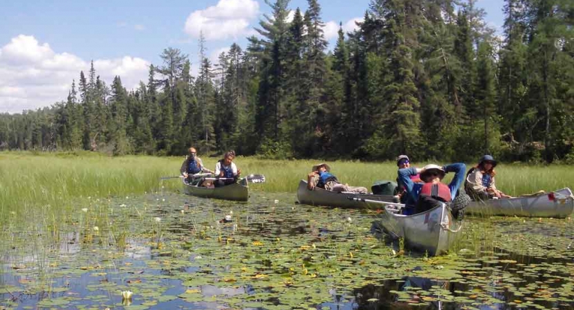 a group of outward bound students rest in their canoes on marsh waters